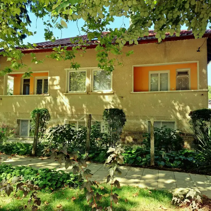 Porodična kuća sa dvorištem i žičanom ogradom od pletiva na stubovima, uz trotoar