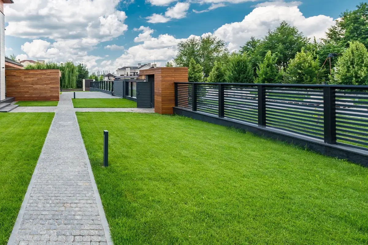 Aluminijumske ograde Beograd: crna ograda od horizontalnih lamela na podzidu, uz travnjak